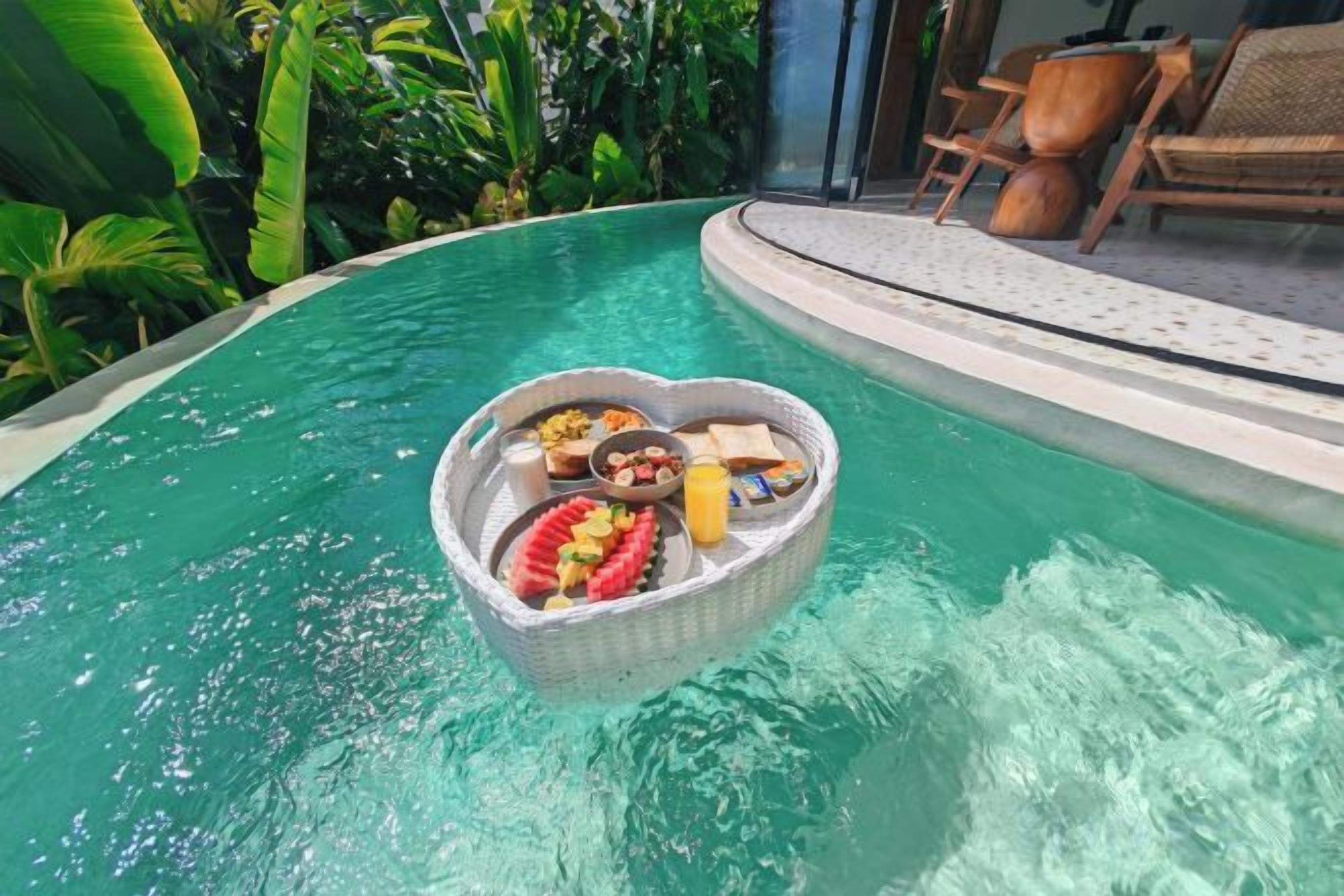 Un panier flottant en forme de cœur, contenant des aliments, dans une piscine.