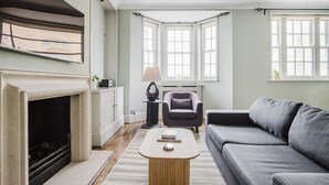 A living room with a fireplace, a sofa, a chair, and a table.