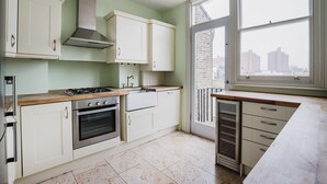 A modern kitchen with white cabinets, a gas stove, an oven, and a large window offering a city view.