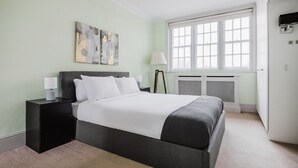 A bedroom with a bed, bedside tables, a lamp, a radiator, and a window.