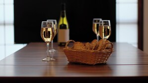 Ein Holztisch mit zwei Weingläsern und einem Brotkorb.