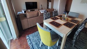 Un saló amb sofà, televisió i menjador amb taula i cadires.