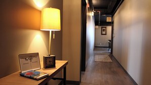A hallway with a lamp, a laptop, and a clock on a table. - 4th Street Lofts (Bemidji)