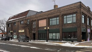 A brick building with large windows, a sign reading "OPEN", and a street with parked cars. - 4th Street Lofts (Bemidji)