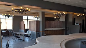A spacious indoor area with a curved counter, multiple tables, chairs, and chandeliers. - 4th Street Lofts (Bemidji)