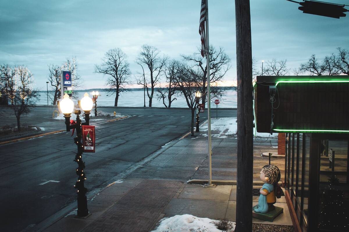 A street view with a sidewalk, a stop sign, a lamp post, and a view of a body of water.
