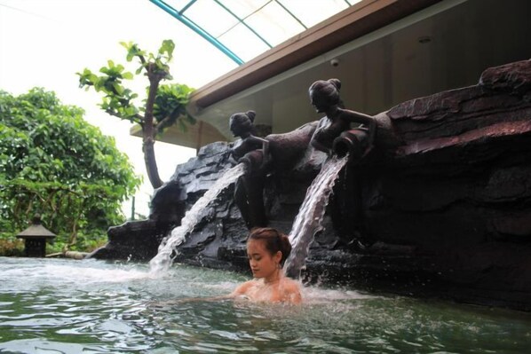 Eine Person in einem Wasserspiel mit einem Wasserfall und Bärenskulpturen.