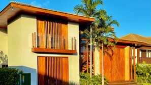 A modern building with a wooden facade, large windows, and a balcony. - High Standard House with 5 Suites with Swimming Pool and Hot Tub in Praia do Forte! (Açu da Torre)