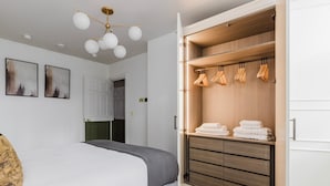 Ein Schlafzimmer mit einem Bett, einem Kleiderschrank mit Kleidung und einer Deckenleuchte.