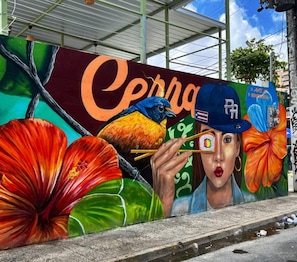 Un mural con un pájaro, flores y una persona sosteniendo palillos.