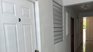 Un pasillo con puertas blancas, suelo de baldosas y un ventilador de techo.