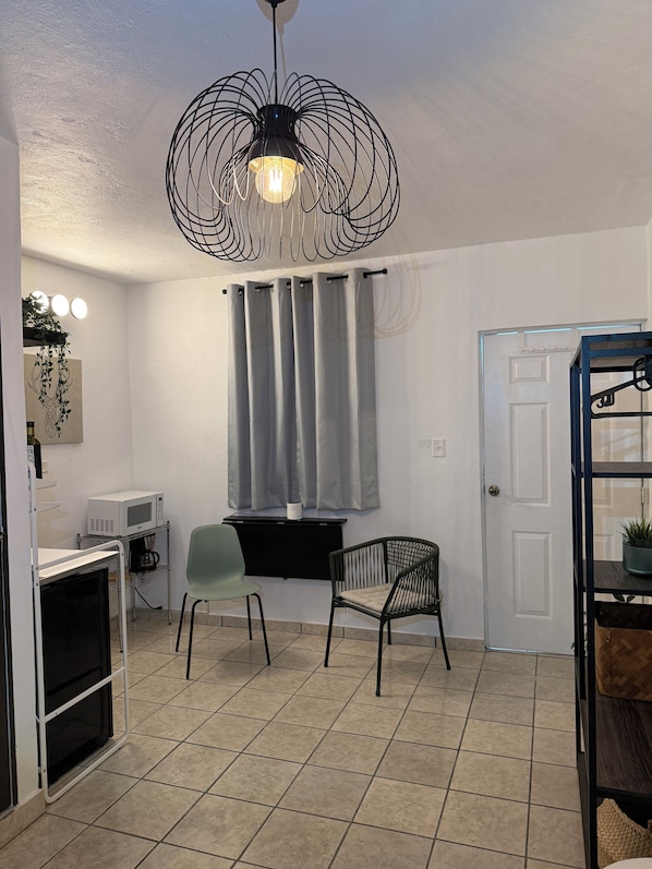 A compact kitchen with a microwave, a coffee machine, and a small dining area with two chairs.