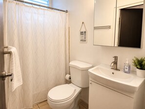 A bathroom with a toilet, sink, and shower curtain. - Cozy Studio - Walk to La Placita - Near Old San Juan (San Juan)