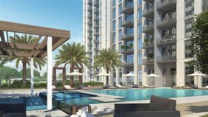 Een modern appartementencomplex met een zwembad op het dak, inclusief ligbedden en parasols.