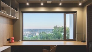 Ein moderner Arbeitsraum mit großem Fenster, Schreibtisch, Stuhl und integrierten Regalen.