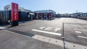 Un hotel con un letrero rojo, un estacionamiento y un edificio con varias unidades.