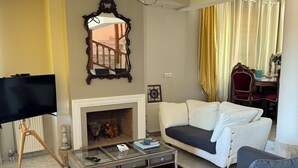 A living room with a sofa, a coffee table, a fireplace, a TV, and a mirror. - Beautiful Tuscan Villa with pool amongst the vineyards and olive trees. (Kato Assos)