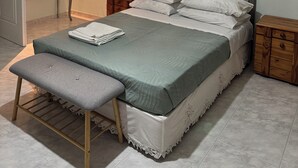 A bedroom with a bed, bench, bedside tables, a wall-mounted light fixture, and a door. - Beautiful Tuscan Villa with pool amongst the vineyards and olive trees. (Kato Assos)