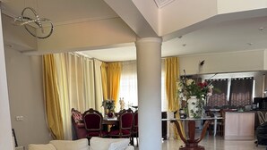 A spacious living area with a sofa, a dining table with chairs, and a kitchen area in the background. - Beautiful Tuscan Villa with pool amongst the vineyards and olive trees. (Kato Assos)
