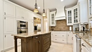 A modern kitchen with white cabinetry, stainless steel appliances, and a granite countertop. - Azure Sky Spacious 5-bedroom house with WiFi and AC in enchanting Naples (Naples)