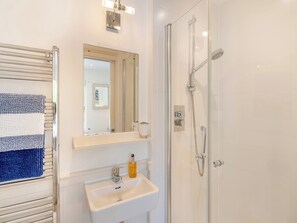 A bathroom with a glass shower enclosure, a white sink with a soap dispenser, and a towel rack with a striped towel. - 2 bedroom accommodation in Hallsands (Hallsands)