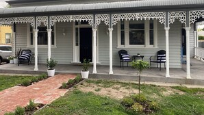 A two-story house with a porch, white columns, and a brick pathway leading to the entrance. - Daisy Cottage - 4 bedrooms, Close to CBD (Golden Square)