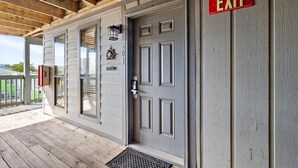 A gray door with a red EXIT sign, a mailbox, and a small decorative item on the wall.
