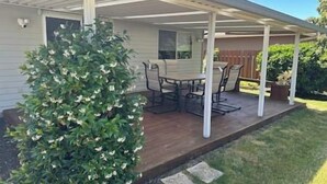A covered patio with a dining table and chairs, surrounded by a small garden and a wooden deck. - A three bedroom house with 2 bathrooms (Gresham)
