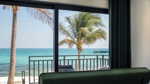 A room with a large window overlooking a beach, a palm tree, and a view of the ocean. - Apsara Resort Koh Rong (Koh Rong)