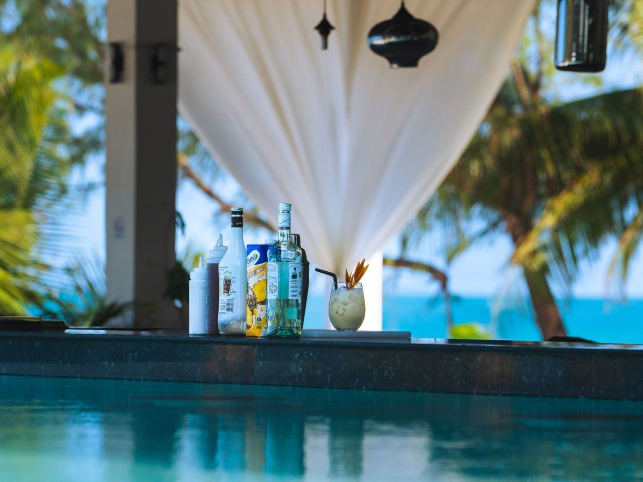 A poolside bar area with bottles and a cocktail glass.
