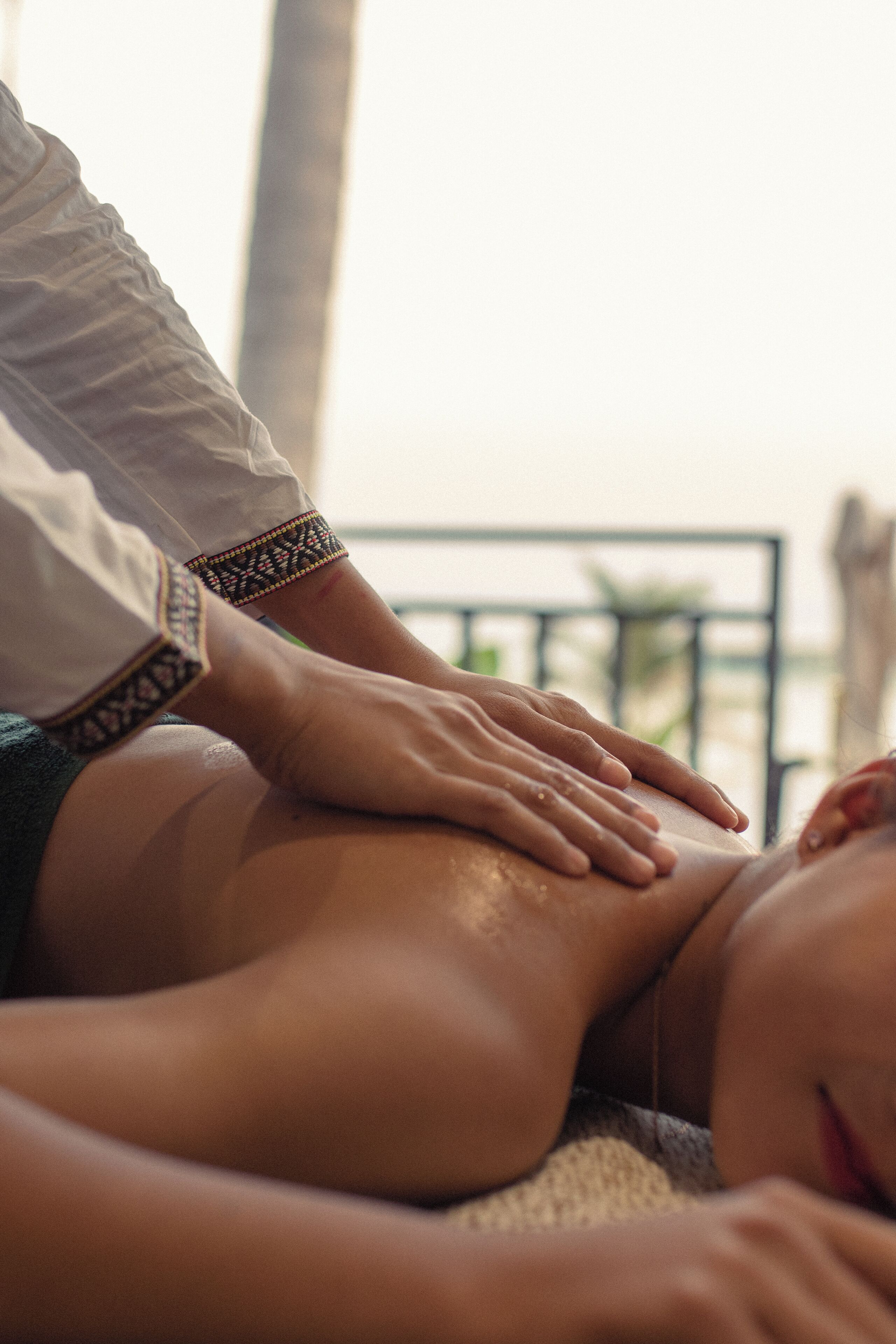 A massage therapy session in progress, with a focus on the hands of the therapist and the client's back.