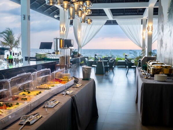 A buffet setup with various food items, a dining area with chairs, and a view of the ocean. - Apsara Resort Koh Rong (Koh Rong)