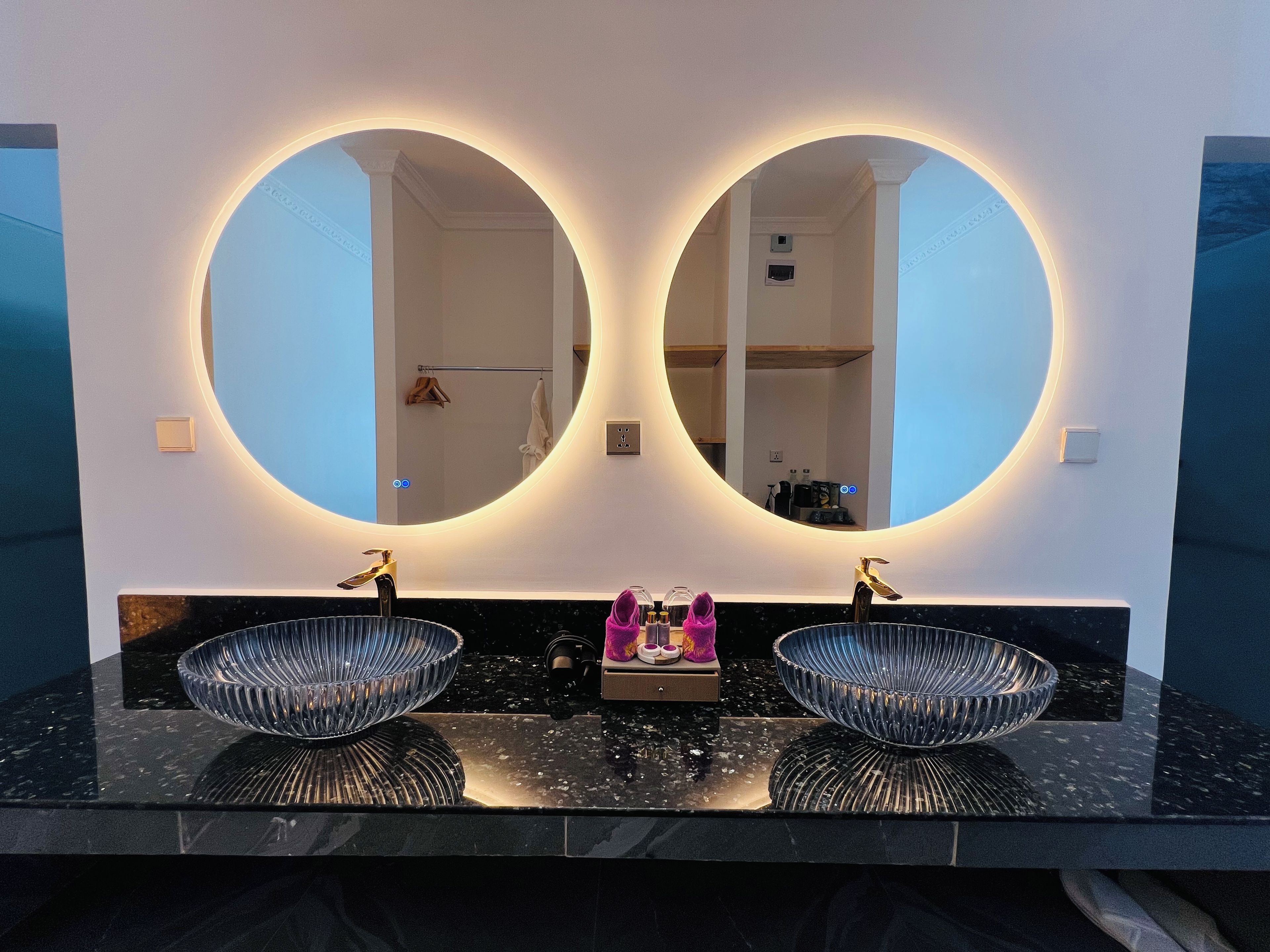 A bathroom with two sinks, each with a large round mirror above.