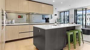 Una cocina moderna con una isla grande, armarios de madera y vistas a la ciudad a través de amplias ventanas.