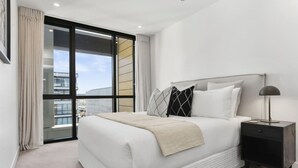 Un dormitorio moderno con una cama grande, una mesita de noche y vistas a través de un ventanal corredizo.