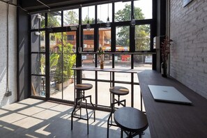A modern interior with large windows, two stools, a table, and a laptop. - Yindee Travellers Lodge by Zuzu (Nan)