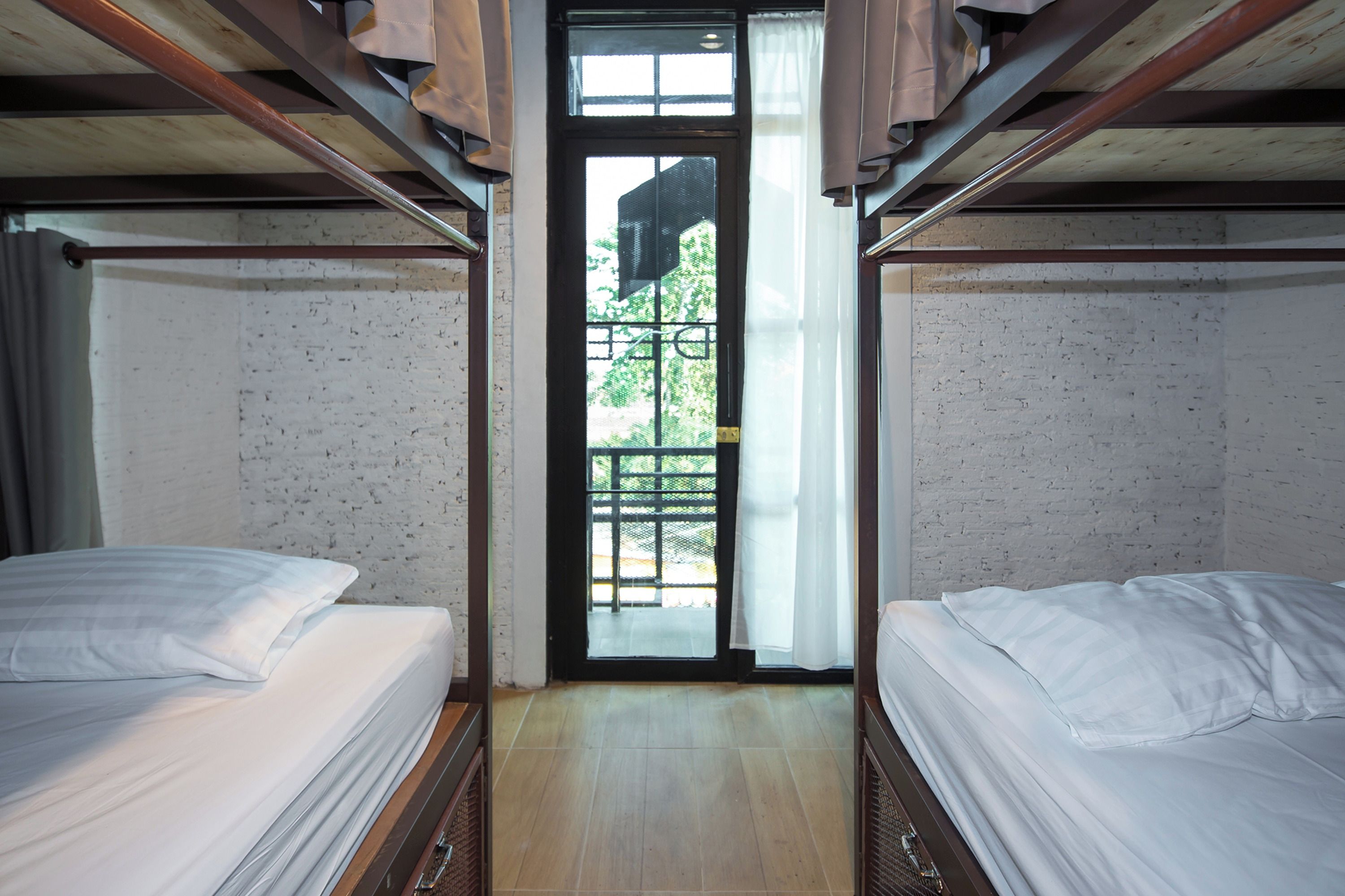 A room with two beds, a wooden ceiling, a door with a view, and a tiled floor.