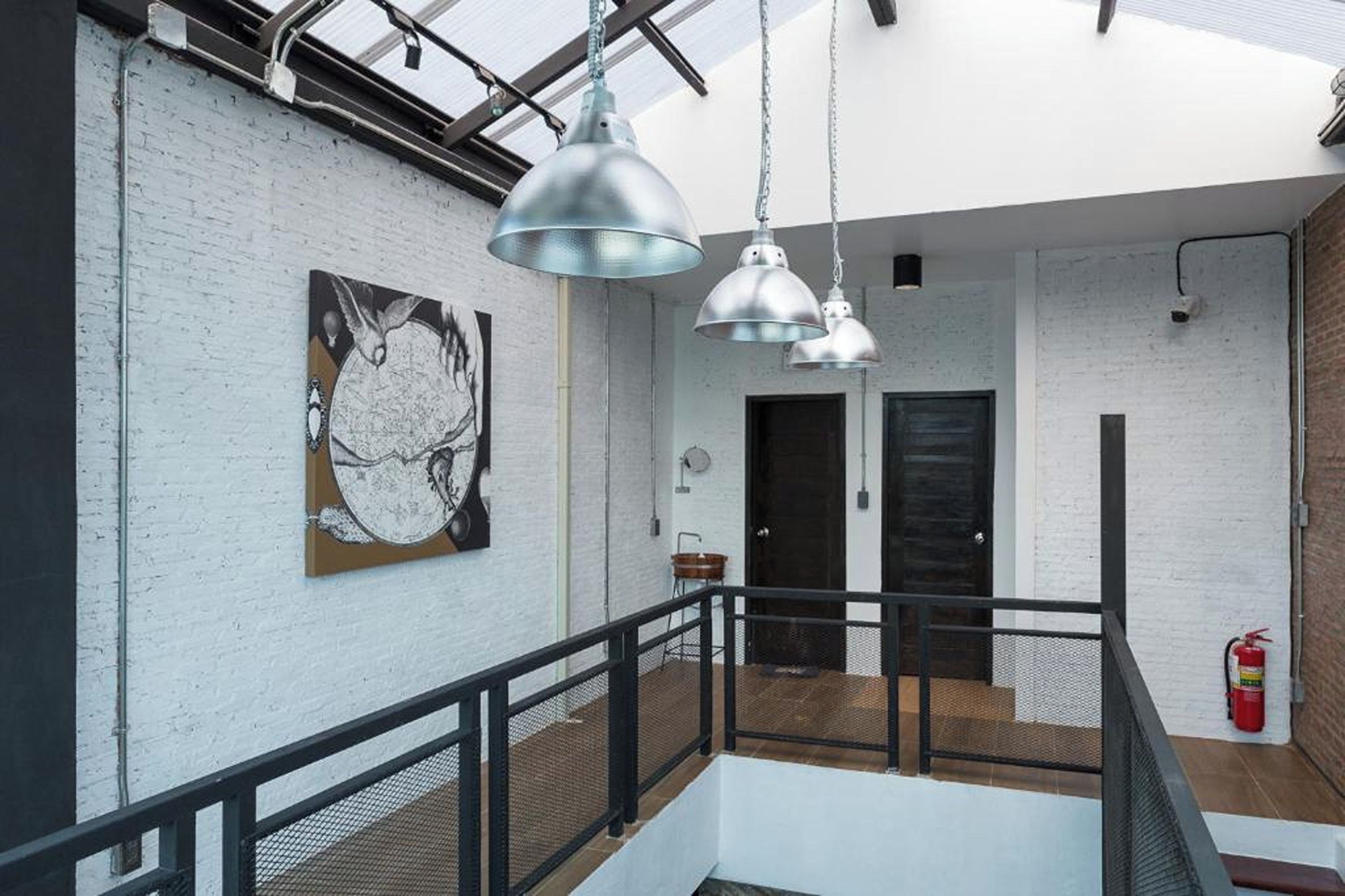 A modern interior with a white brick wall, a large abstract painting, and three hanging pendant lights.