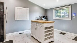 Una cocina con un armario blanco, una ventana y un refrigerador.