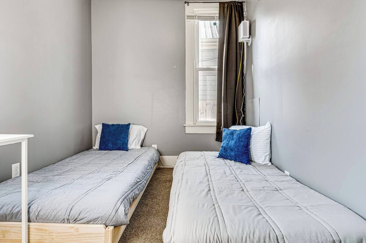 Een slaapkamer met twee bedden, een raam met gordijnen en een witte tafel.