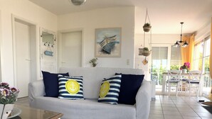 Un salon avec un canapé gris, des coussins à rayures, un tapis à rayures et un tableau accroché au mur.