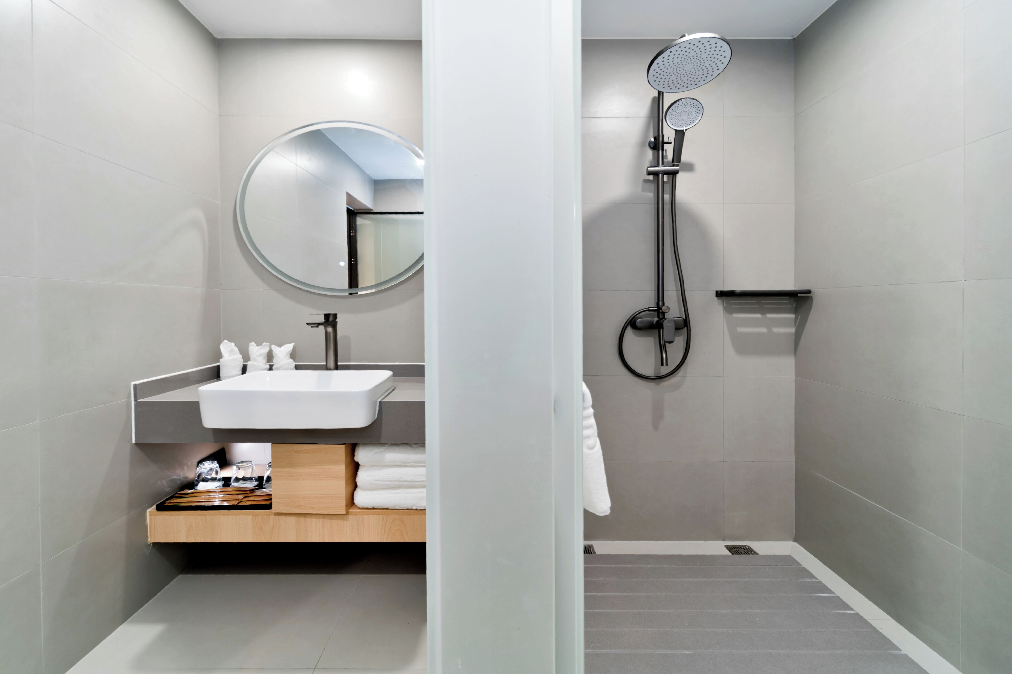A modern bathroom with a white sink, mirror, and shower.