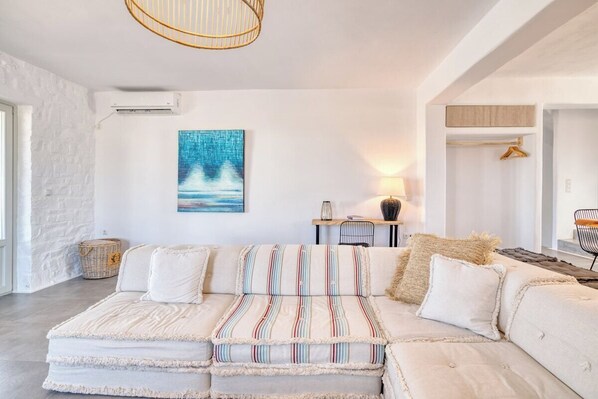 A modern living room with a sectional sofa, a hanging light fixture, and a painting on the wall.