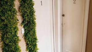 Een trap met een houten leuning die leidt naar twee witte deuren met de cijfers 1 en 2.