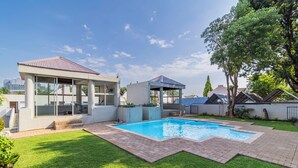 A modern outdoor pool area with a covered seating area and a small pavilion.