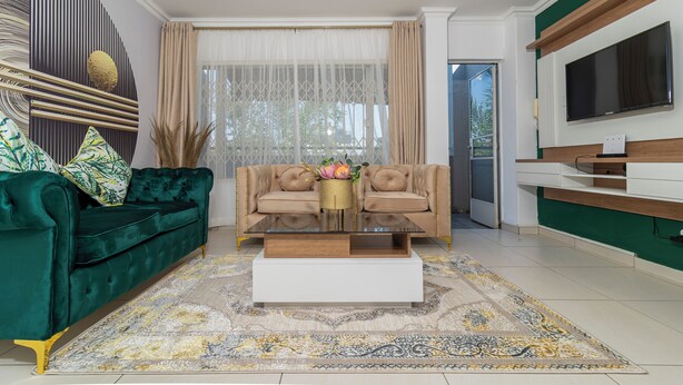 A modern living room with a green sofa, a beige sofa, and a coffee table with decorative items.