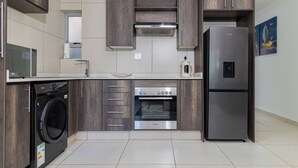 A modern kitchen with dark wood cabinets, a Bosch oven, a Bosch washing machine, and a large refrigerator.