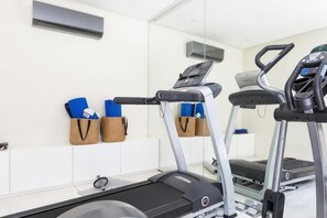 Une salle de remise en forme équipée de tapis de course, de ballons d’exercice et d’étagères murales.