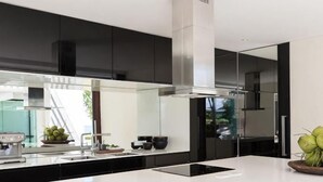 A modern kitchen with black cabinets, a white countertop, and a stainless steel range hood. - Fashionable Villa Malabar Beachfront 5 Bedrooms Plus 2 Kid's Bedrooms 10+6 (Koh Samui)