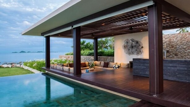 A modern outdoor pool area with a view of the sea, a wooden deck, and a seating area with cushions. - Fashionable Villa Malabar Beachfront 5 Bedrooms Plus 2 Kid's Bedrooms 10+6 (Koh Samui)